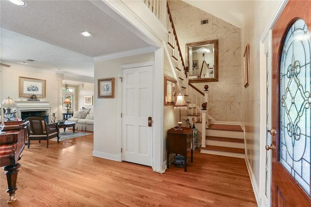 entrance foyer with light hardwood / wood-style floors, ornamental molding, and a textured ceiling