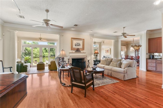 living room featuring crown molding, a textured ceiling, and light wood-type flooring