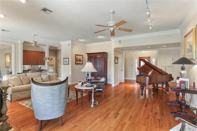 living room featuring rail lighting, ornamental molding, light hardwood / wood-style flooring, and ceiling fan