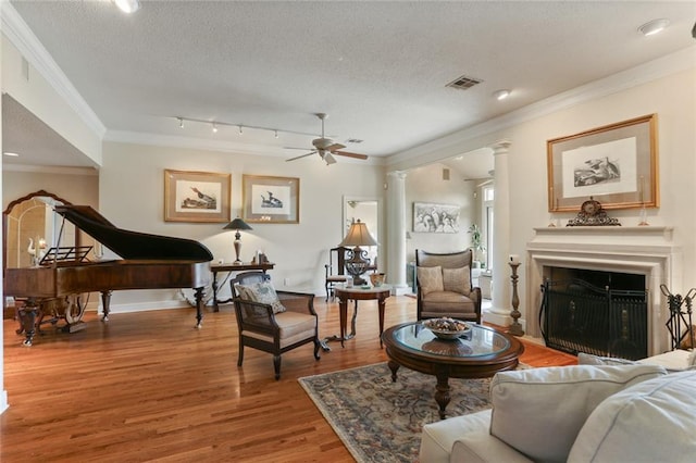 living room with ornamental molding, a textured ceiling, wood-type flooring, and ceiling fan