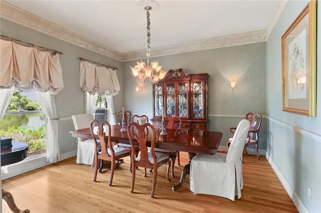 dining area with a notable chandelier, ornamental molding, and hardwood / wood-style floors