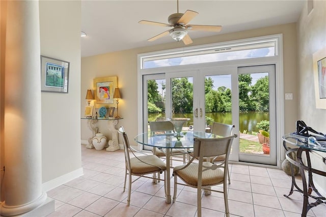 tiled dining area with french doors, ceiling fan, a water view, and decorative columns