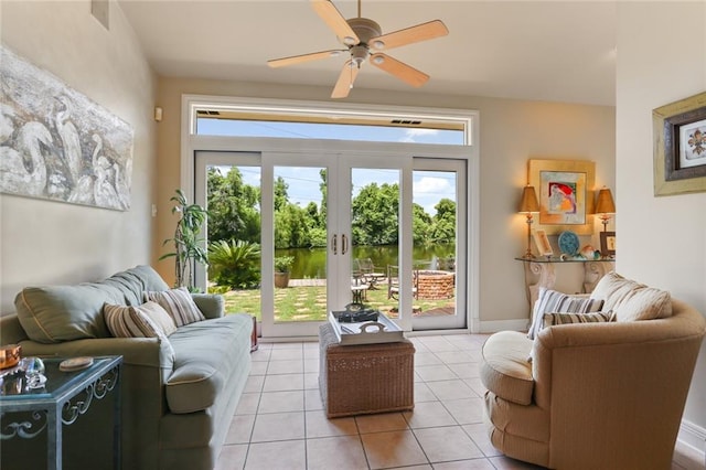 tiled living room with french doors, a water view, and ceiling fan