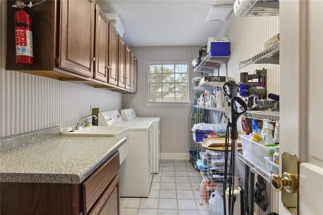 washroom featuring washer and clothes dryer, a textured ceiling, cabinets, and light tile patterned floors