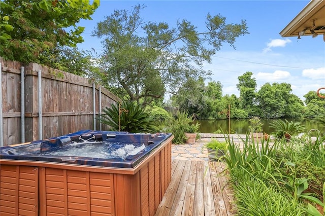 deck with a hot tub and a water view