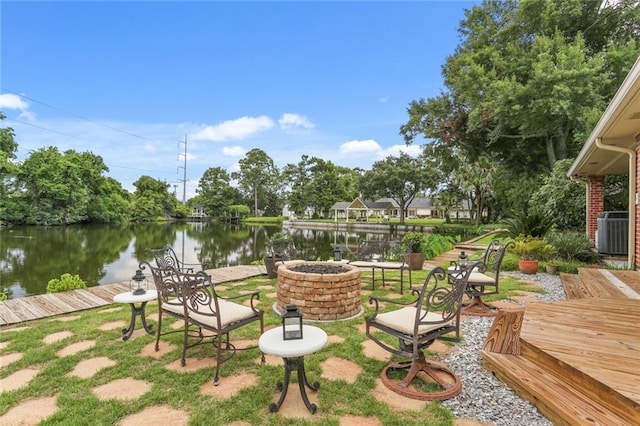 exterior space with central AC, a deck with water view, and a fire pit