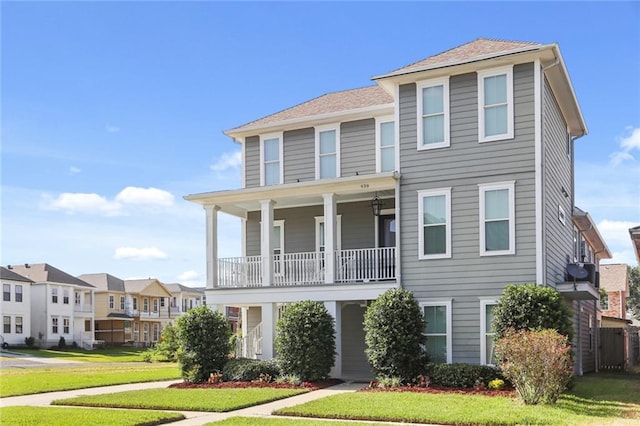 view of front facade with a balcony and a front lawn