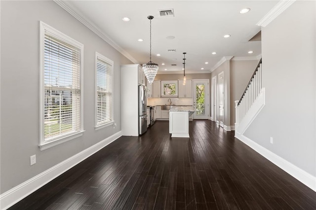 kitchen with a center island, dark wood-type flooring, hanging light fixtures, crown molding, and stainless steel fridge