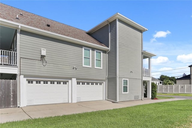 view of side of property featuring a balcony, a lawn, and a garage