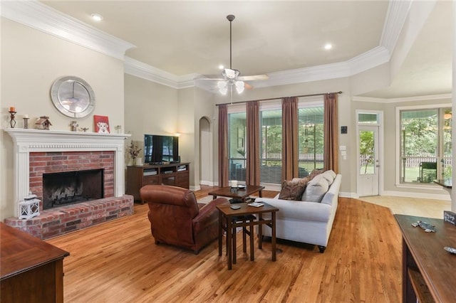 living room featuring ceiling fan, a wealth of natural light, light hardwood / wood-style flooring, and a fireplace