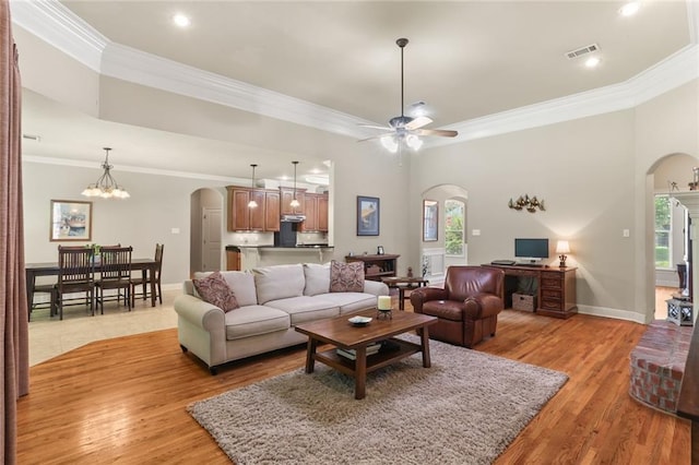 living room with ceiling fan with notable chandelier, a healthy amount of sunlight, crown molding, and light hardwood / wood-style floors