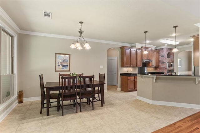 dining area with a chandelier, crown molding, and light tile patterned floors