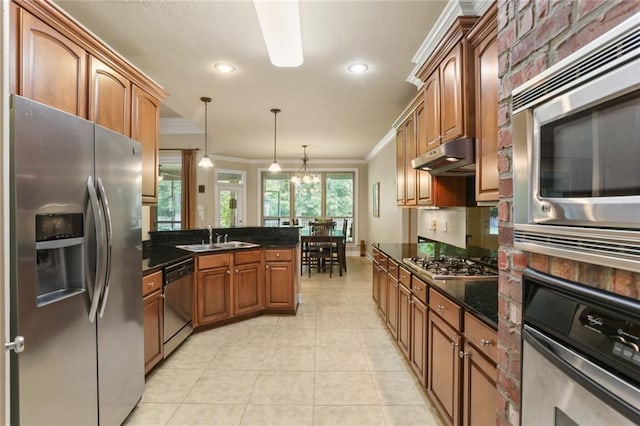 kitchen featuring crown molding, appliances with stainless steel finishes, sink, decorative light fixtures, and dark stone countertops