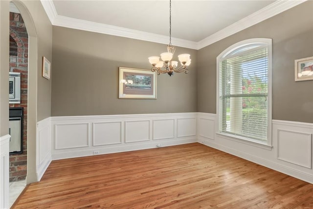 unfurnished room featuring ornamental molding, light hardwood / wood-style floors, and an inviting chandelier