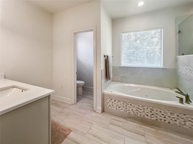 bathroom featuring tiled bath, toilet, and vanity