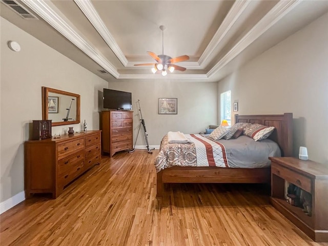 bedroom featuring ceiling fan, light hardwood / wood-style floors, crown molding, and a raised ceiling