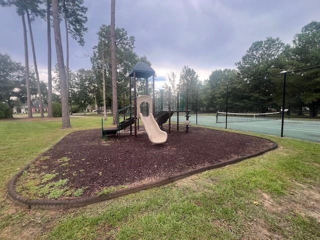 view of playground featuring tennis court and a lawn