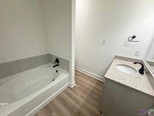 bathroom featuring vanity, hardwood / wood-style floors, and a bath