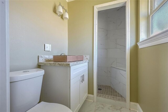 bathroom with vanity, toilet, and tiled shower