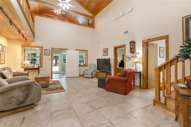 tiled living room with wood ceiling, high vaulted ceiling, rail lighting, and ceiling fan