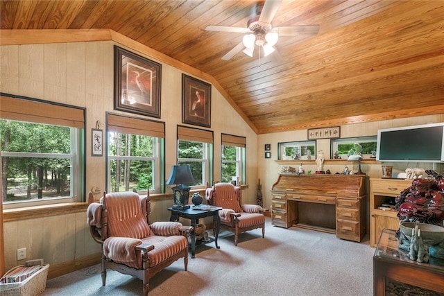 living area featuring vaulted ceiling, wooden ceiling, wooden walls, ceiling fan, and carpet