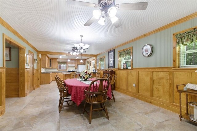 dining space with ornamental molding, ceiling fan with notable chandelier, and light tile patterned floors