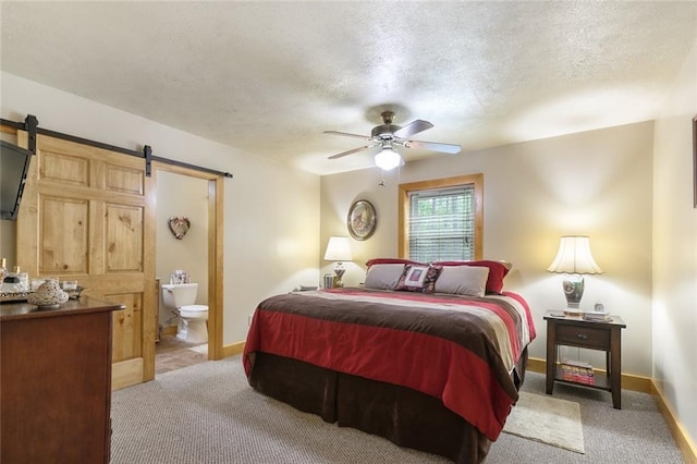 carpeted bedroom featuring ceiling fan, connected bathroom, a barn door, and a textured ceiling