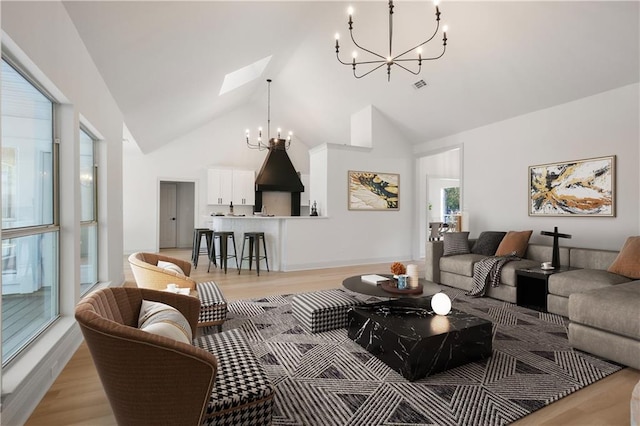 living room with a skylight, light wood-type flooring, high vaulted ceiling, and a chandelier