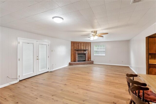 living room featuring a brick fireplace, french doors, ceiling fan, and light wood-type flooring