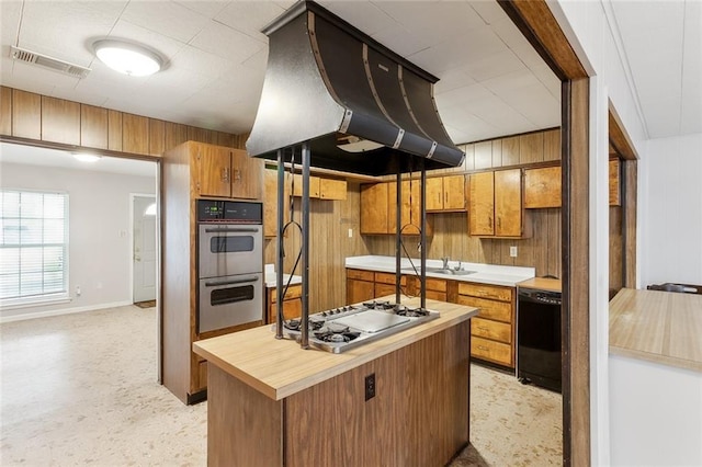 kitchen featuring appliances with stainless steel finishes, wooden walls, sink, and exhaust hood