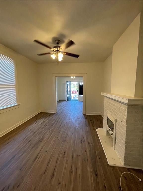 unfurnished living room with ceiling fan, a fireplace, and dark hardwood / wood-style flooring