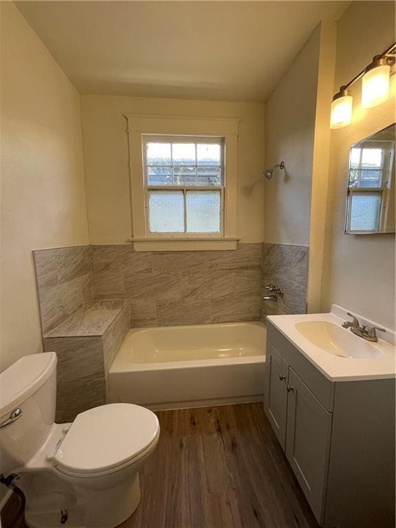 bathroom with hardwood / wood-style flooring, vanity, toilet, and a bathtub