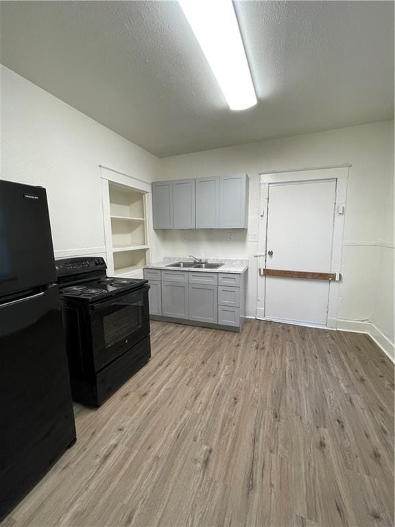 kitchen with sink, a textured ceiling, gray cabinets, built in features, and black appliances