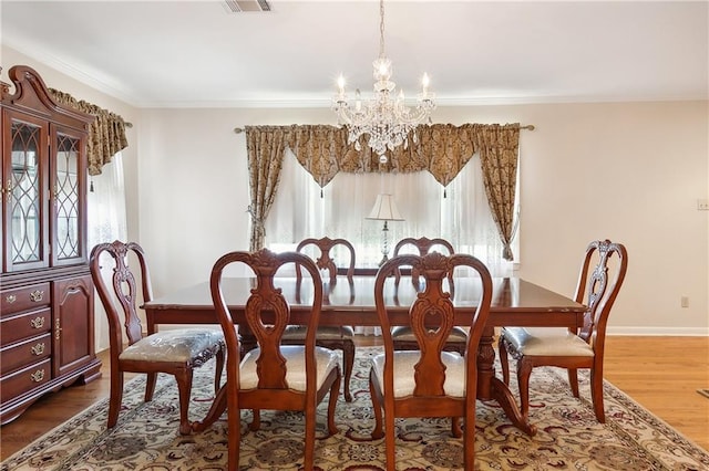 dining space with crown molding, a healthy amount of sunlight, wood-type flooring, and a notable chandelier