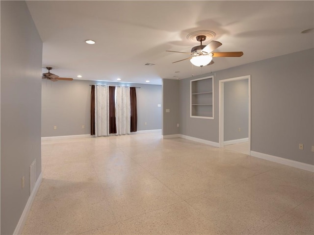 empty room featuring built in shelves and ceiling fan