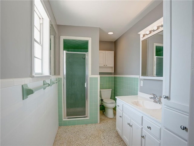 bathroom with an enclosed shower, tile walls, toilet, and vanity