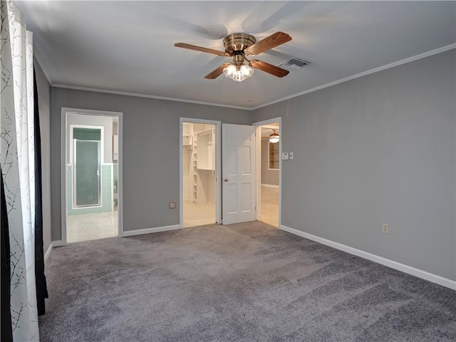 unfurnished bedroom featuring ceiling fan, a closet, a spacious closet, and crown molding