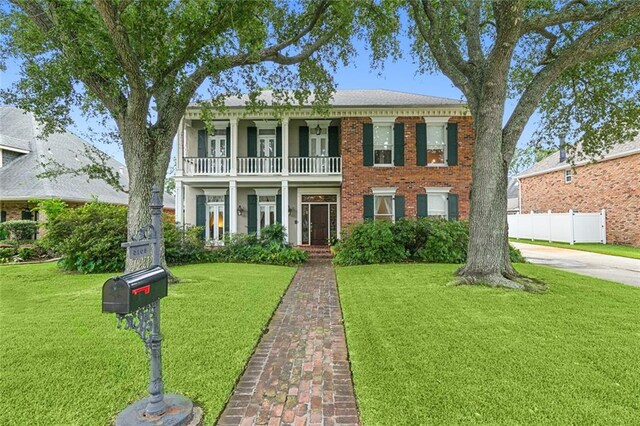 colonial-style house with a balcony and a front yard