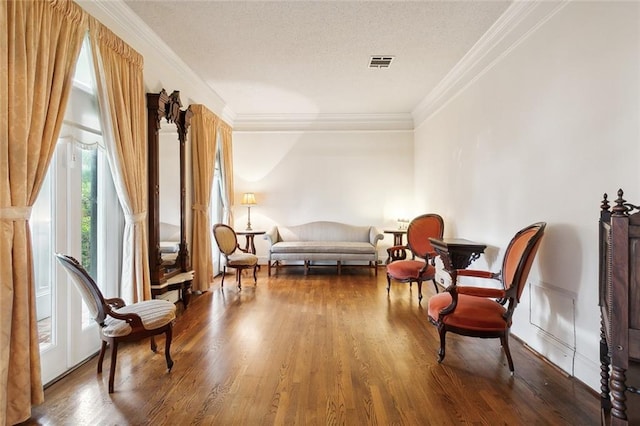 living area featuring wood-type flooring, crown molding, and a textured ceiling