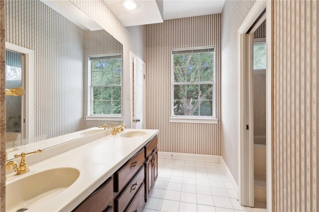 bathroom with tile patterned flooring, a wealth of natural light, and double sink vanity