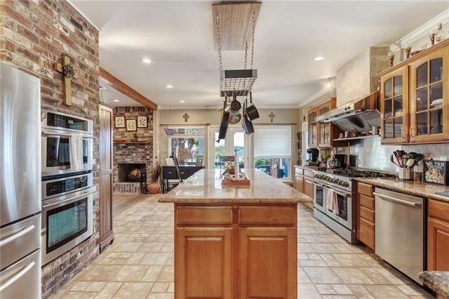 kitchen featuring a center island, a fireplace, light tile floors, and appliances with stainless steel finishes