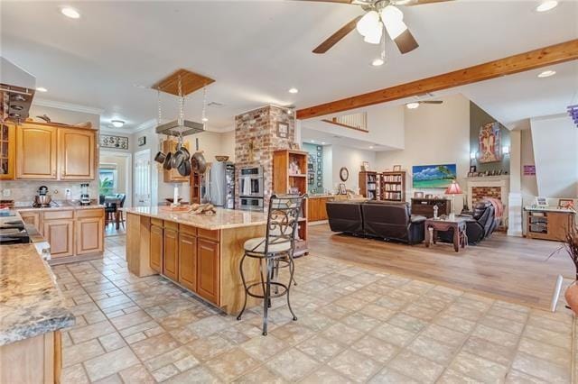 kitchen featuring double oven, brick wall, ceiling fan, a center island, and light tile floors