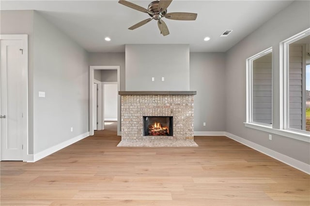 unfurnished living room featuring ceiling fan, a fireplace, and light hardwood / wood-style flooring