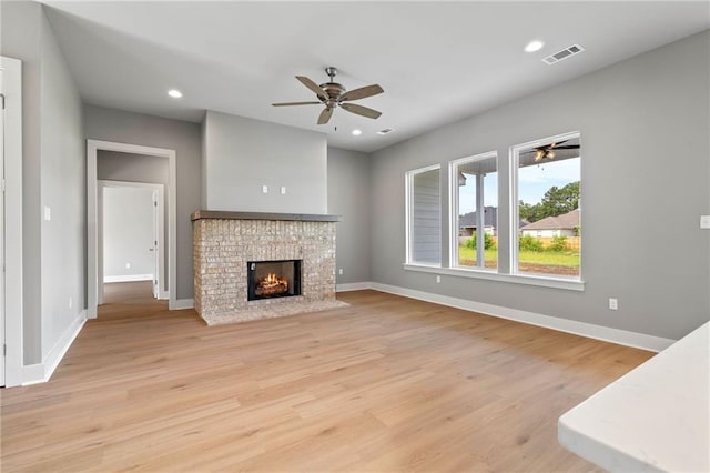 unfurnished living room featuring ceiling fan, a fireplace, and light wood-type flooring