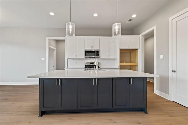 kitchen featuring a spacious island, decorative light fixtures, sink, and white cabinets