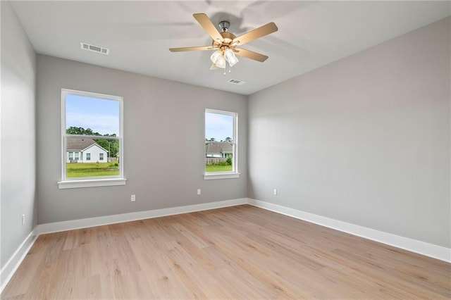 spare room featuring ceiling fan, light hardwood / wood-style floors, and a wealth of natural light