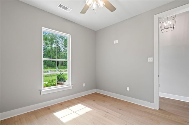 unfurnished room featuring ceiling fan with notable chandelier and light wood-type flooring