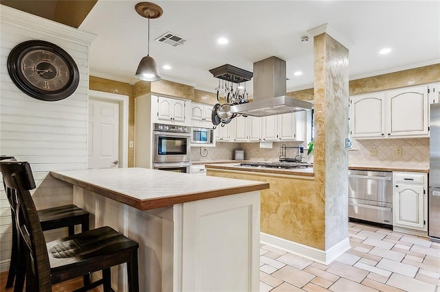 kitchen with white cabinets, decorative backsplash, appliances with stainless steel finishes, decorative light fixtures, and island range hood