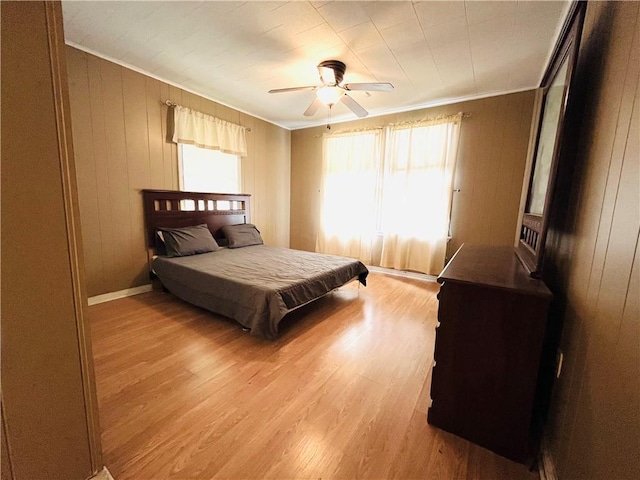 651 Avenue E Ave E, Westwego, LA 70094 - bedroom featuring ornamental molding, light wood-type flooring, a ceiling fan, and wood walls