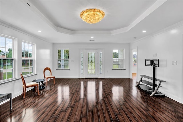 entrance foyer with dark hardwood / wood-style floors, a raised ceiling, crown molding, and an inviting chandelier